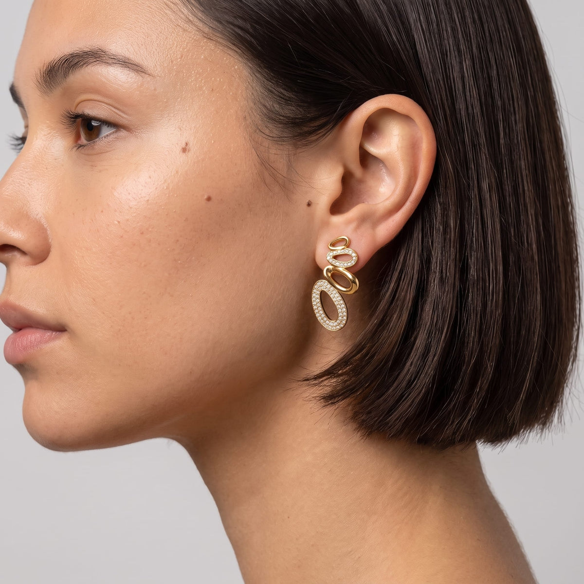 Woman wearing the Agathe pavé oval gold earrings on the ear in profile view