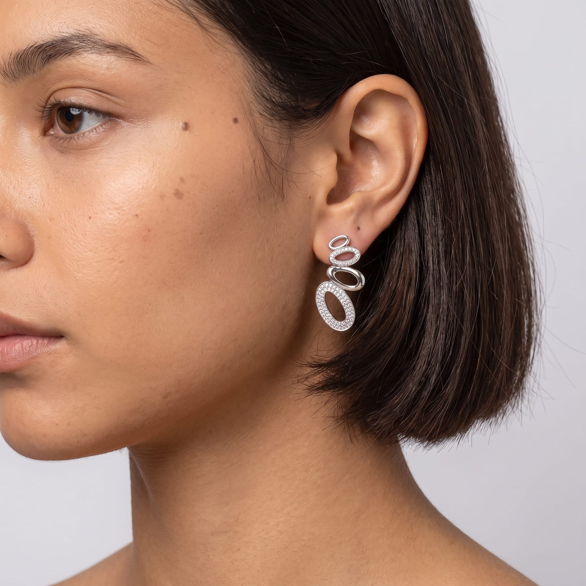 Woman wearing the Agathe pavé oval silver earrings on the ear in a close-up profile shot