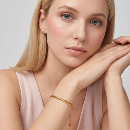 Blonde woman resting her chin on her arms, wearing the Alessia snake chain gold bracelet