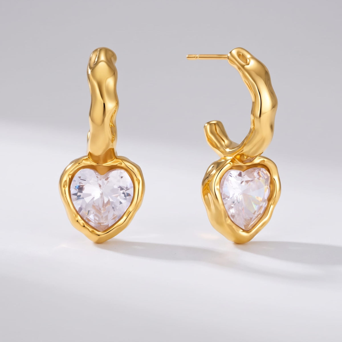 Amandine hammered heart gold earrings on a plain white surface with soft shadows