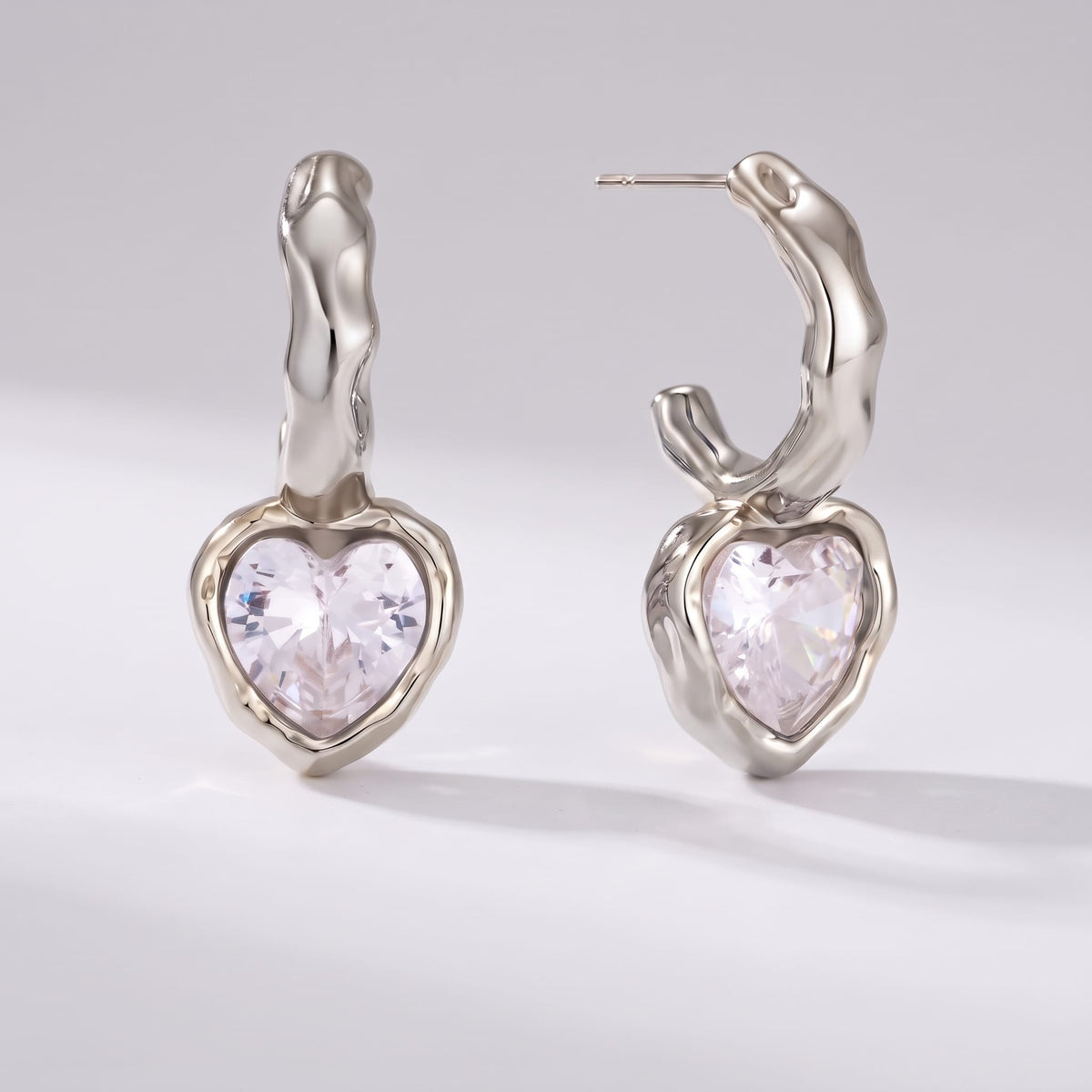 Amandine hammered heart silver earrings on a plain light background shown from front and side view