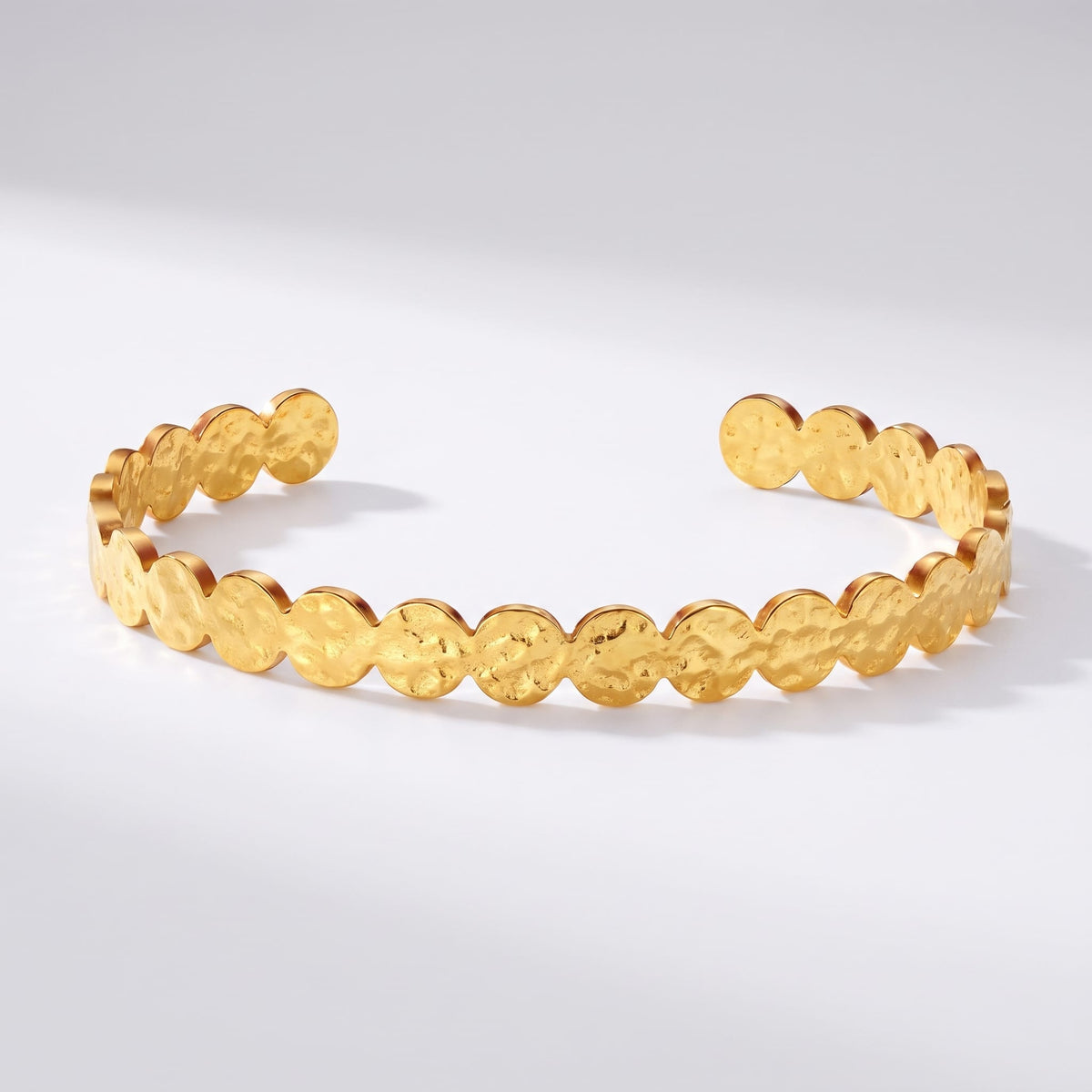Ambre hammered cuff gold bracelet on a white surface with soft shadows