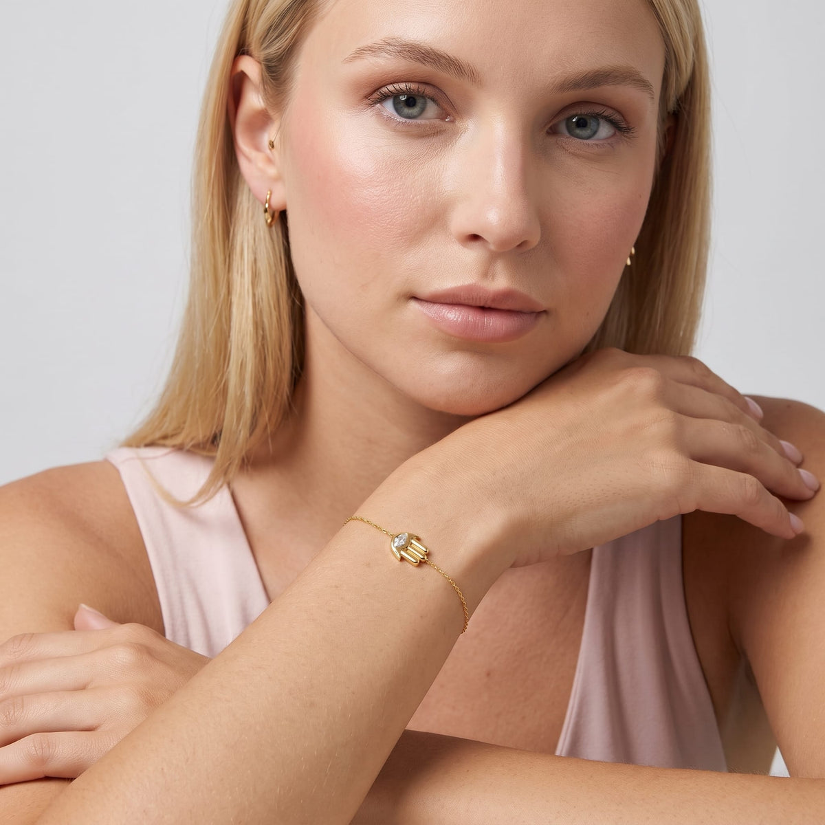 Woman wearing the Amelia crystal hamsa gold bracelet on the wrist while leaning on her hand
