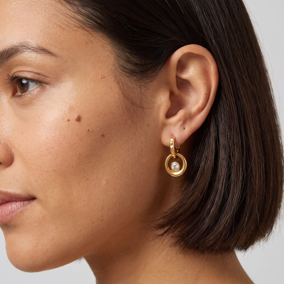 Woman wearing the Amélie circle drop gold earrings on the ear with short dark hair