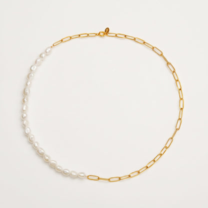The Amélie pearl paperclip gold necklace laid flat on an off-white surface