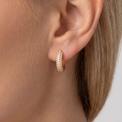 Woman wearing the Amy chunky gold huggie paved with rows of crystals