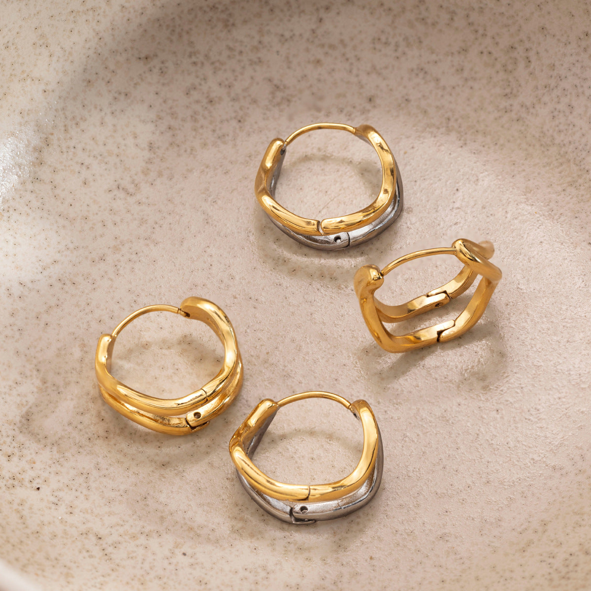 Anouk two-tone hoops with silver back bands among gold pairs in a stoneware dish