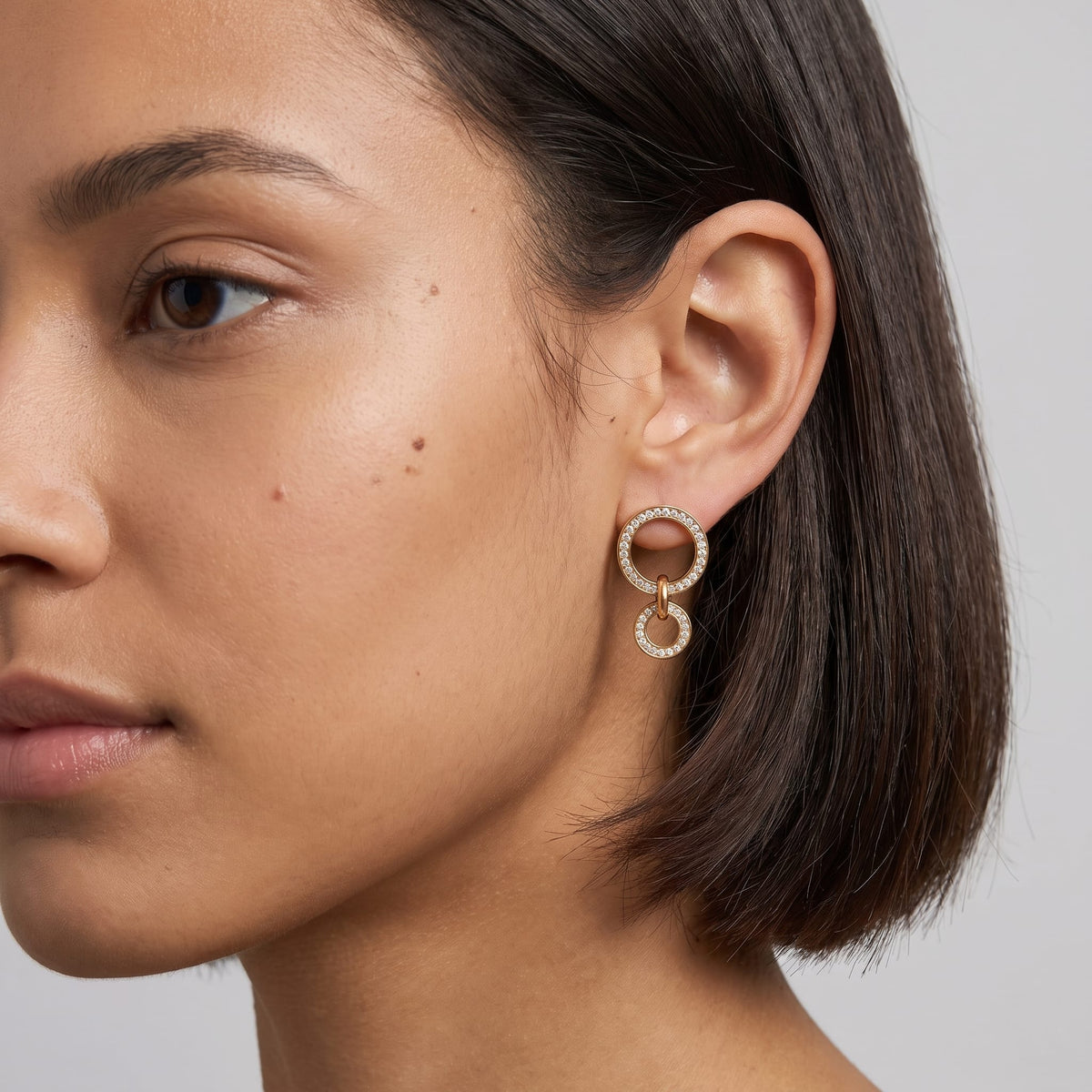 Woman wearing the Apolline double circle gold earrings on the ear with dark short hair in profile view