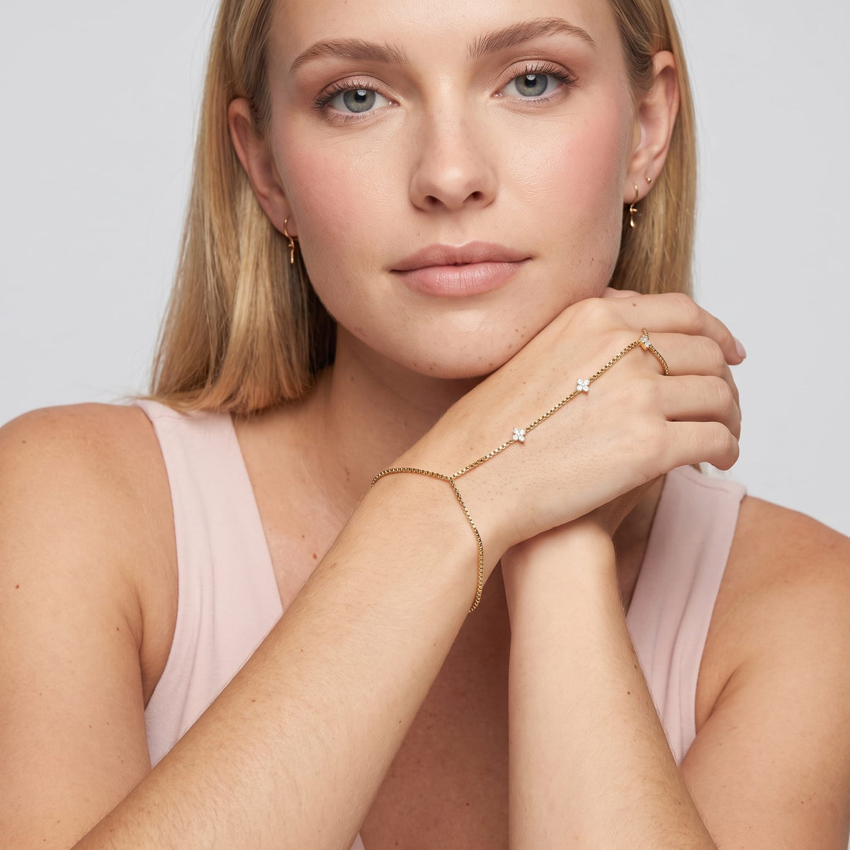 Woman wearing the Apolline hand chain gold bracelet on the hand while resting chin on her hand