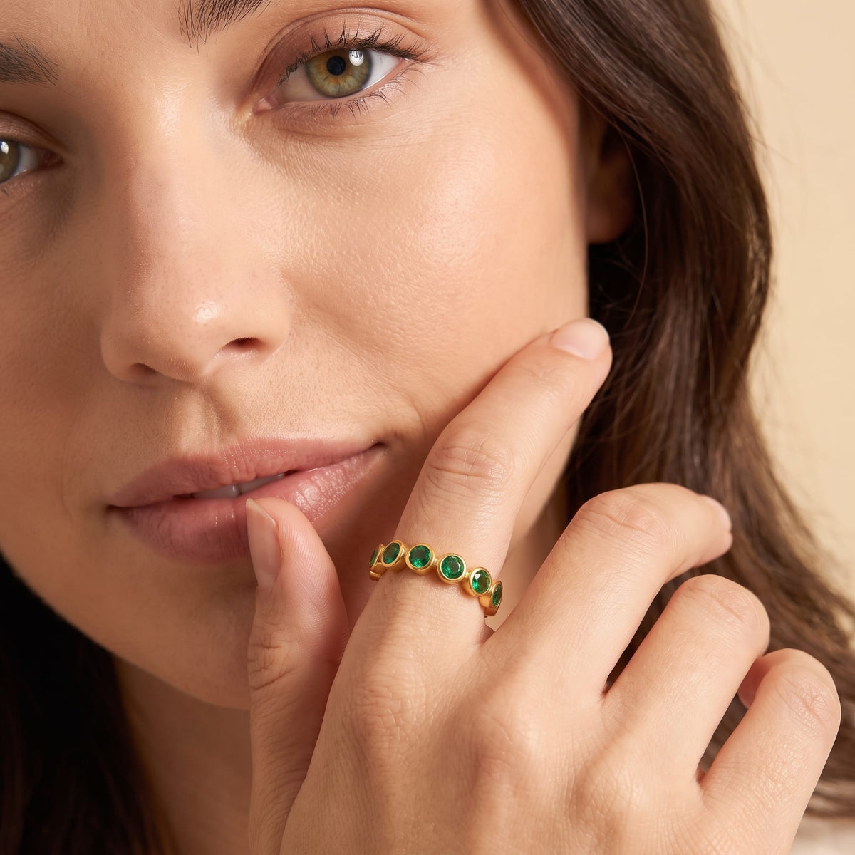 Woman wearing the Ariana green round gold ring on the hand touching her lip