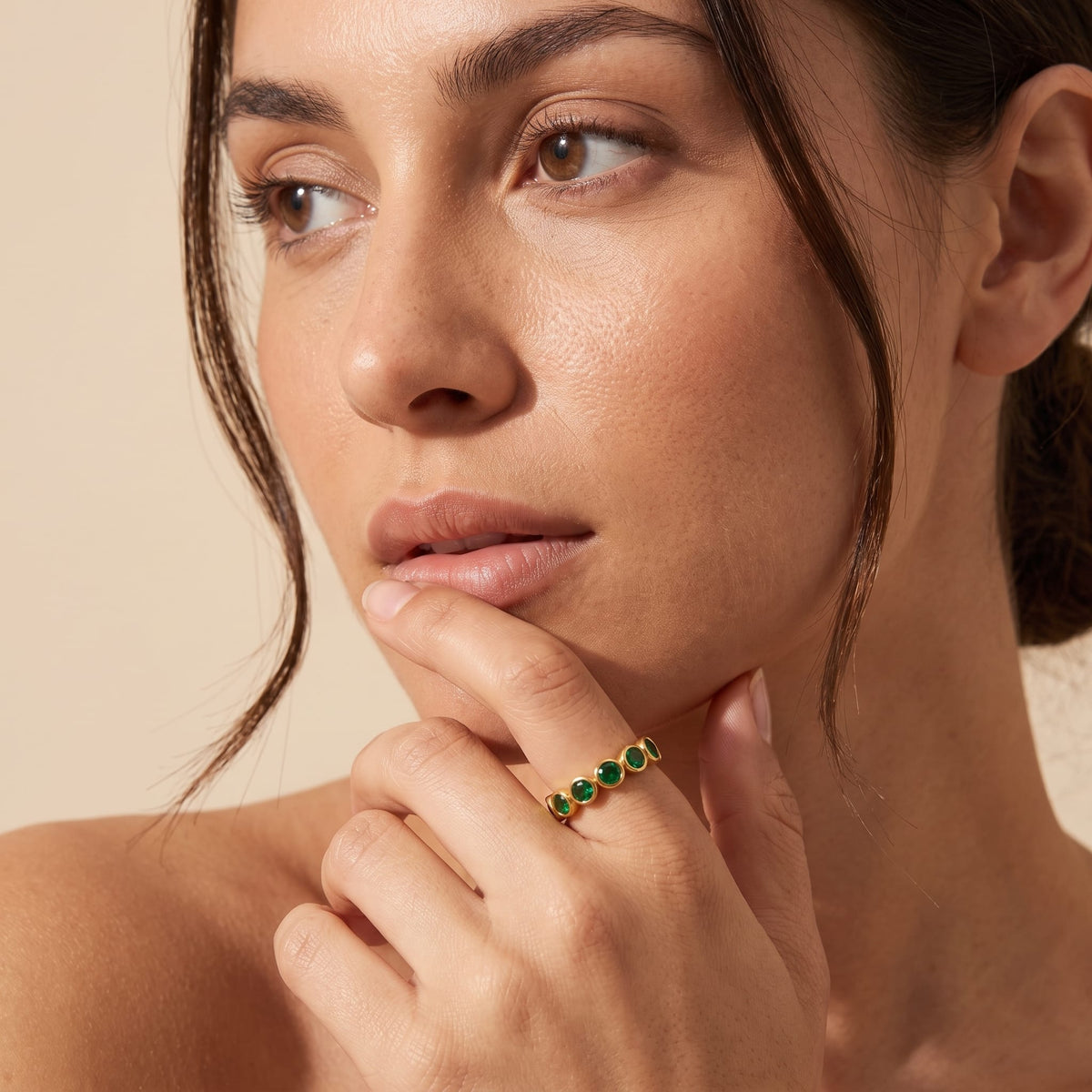 Woman wearing the Ariana green round gold ring on the hand posing near chin