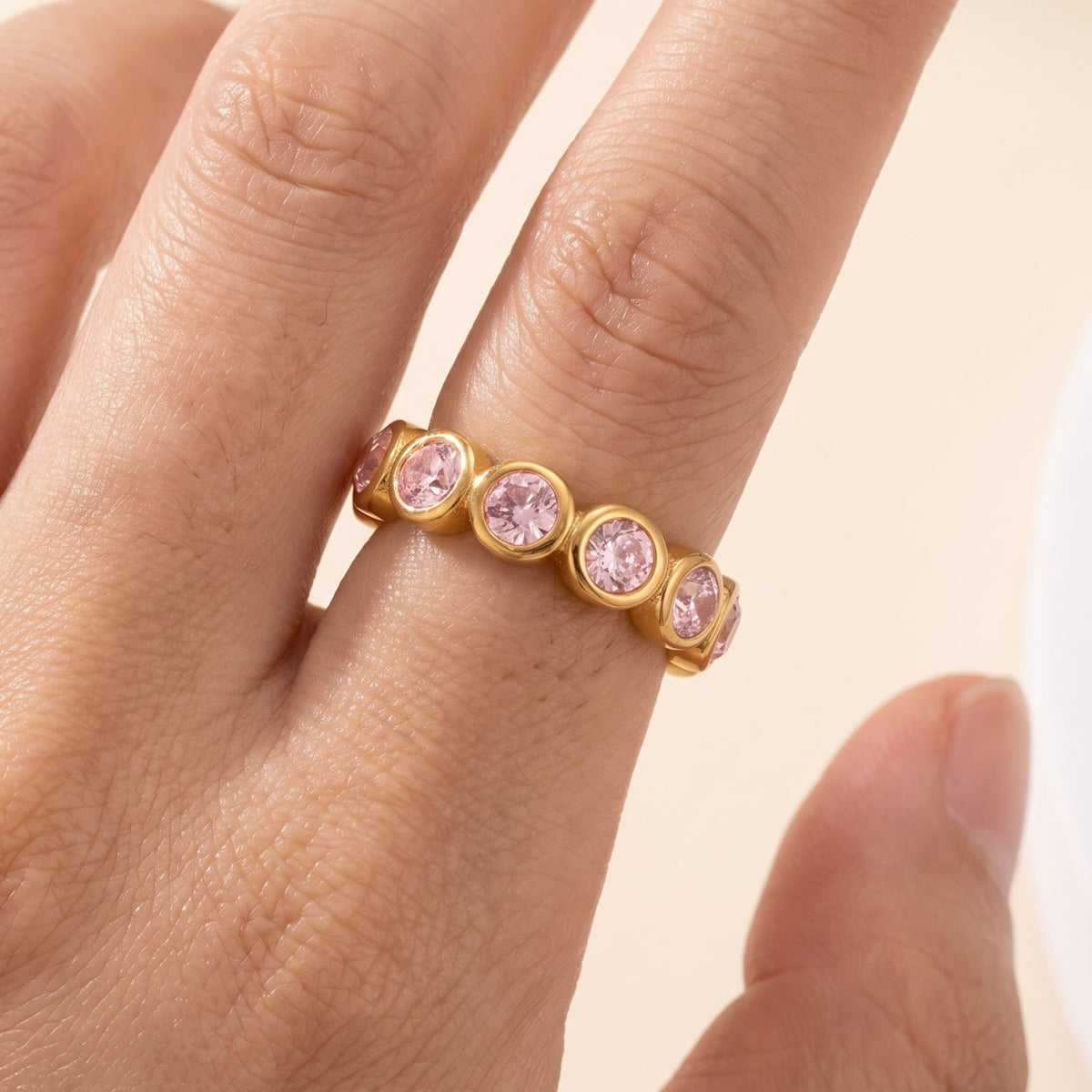 Woman wearing the Ariana pink round gold ring on the hand, set with pink crystals