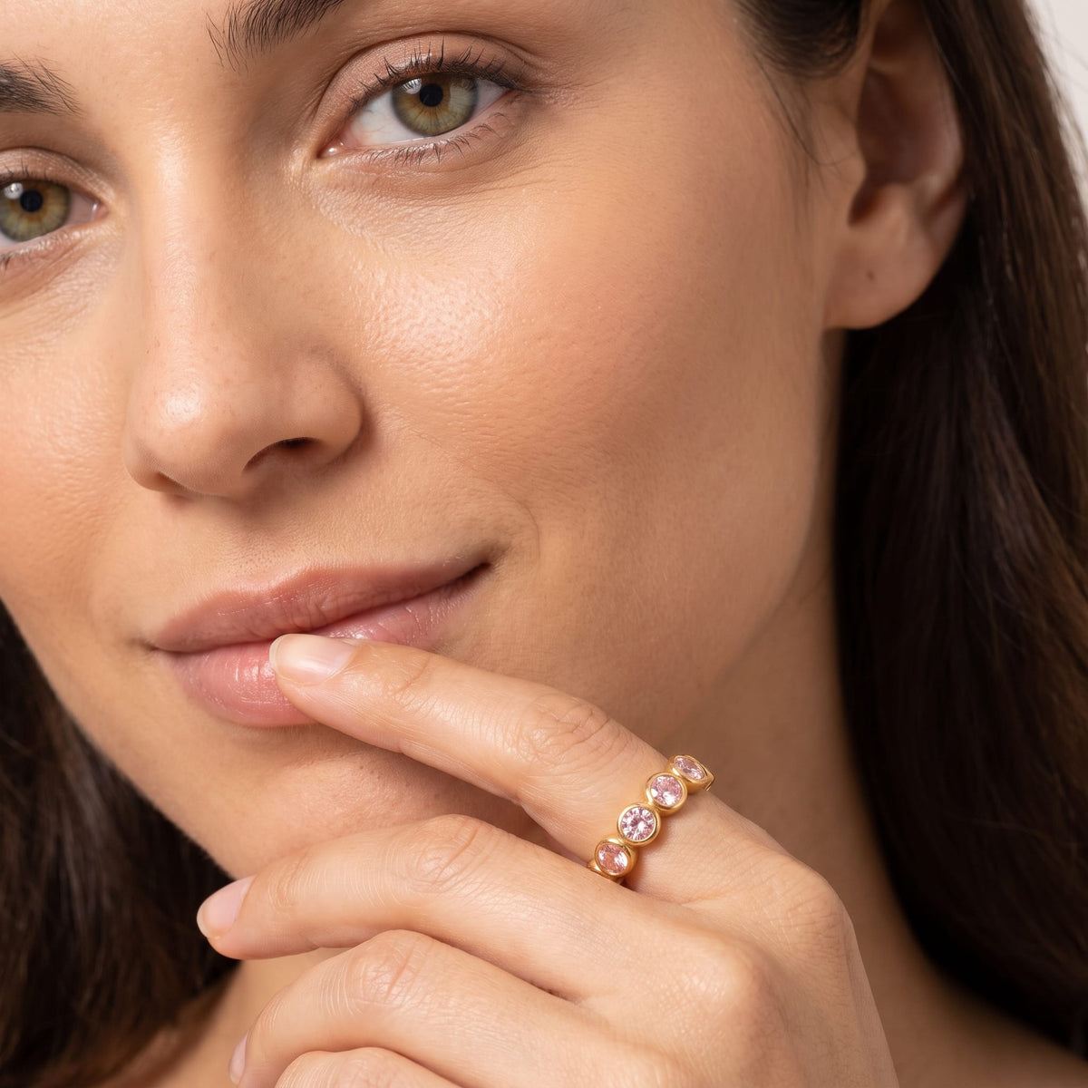 Woman wearing the Ariana pink round gold ring on the hand touching her lips