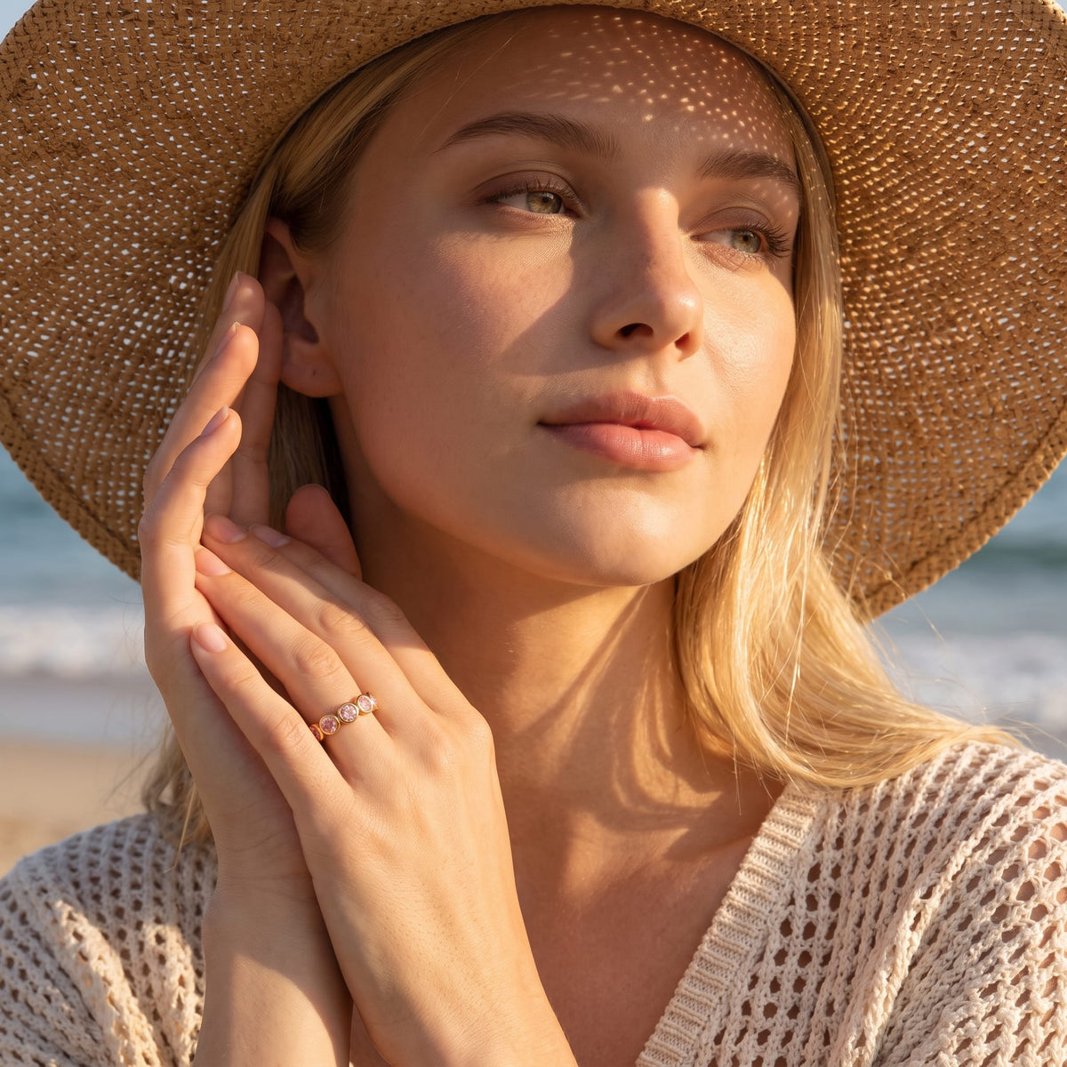 Woman wearing the Ariana pink round gold ring on the hand at the beach