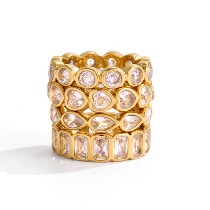 Stack of four clear crystal eternity gold rings, the round bezel band on top