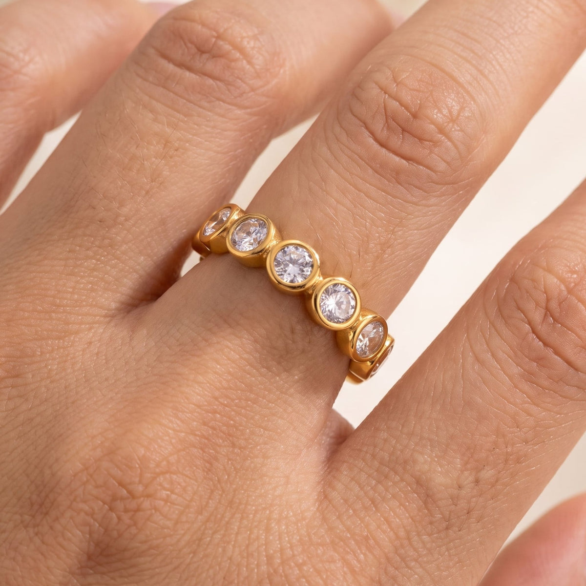 Woman wearing the Ariana round eternity gold ring on the hand, set with round crystals