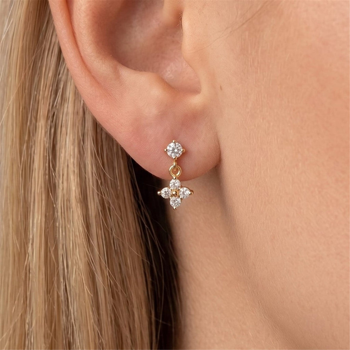 Woman wearing an Astrid gold earring, a crystal clover hanging beneath a small round crystal stud