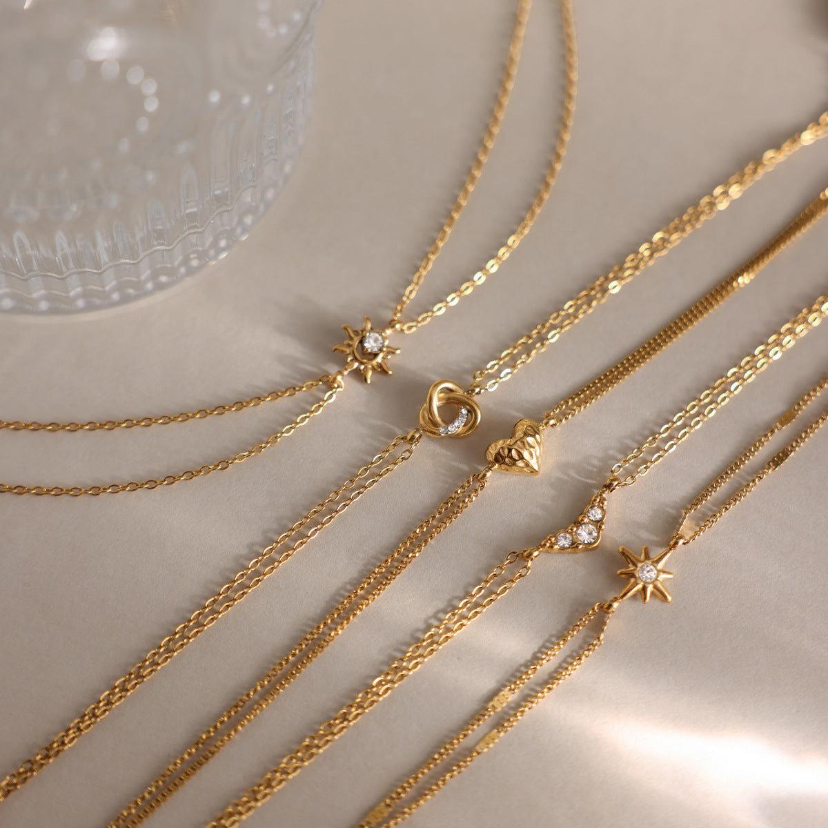 Astrid north star bracelet laid diagonally with other fine charm bracelets on satin