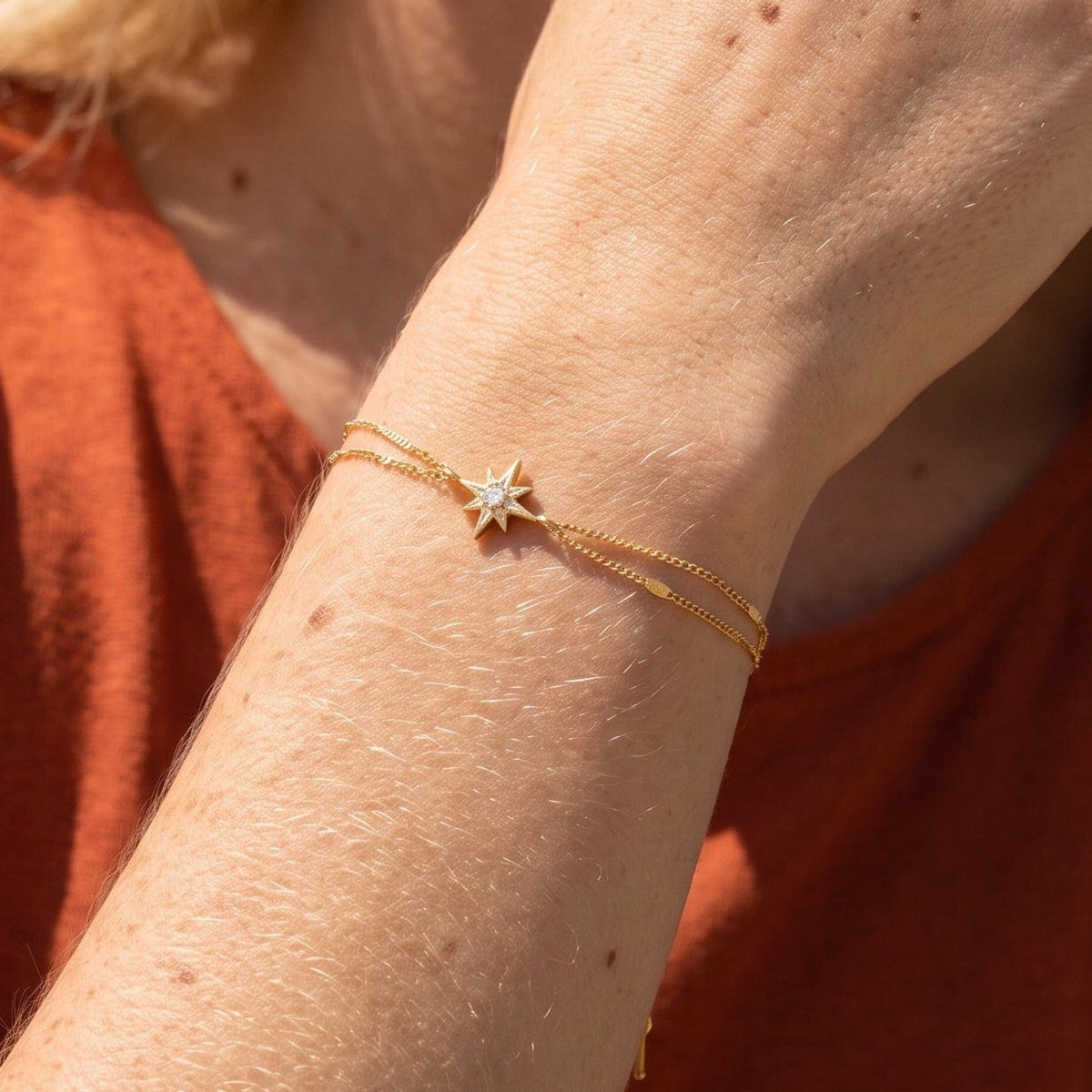 Woman wearing the Astrid north star gold bracelet on the wrist, featuring a star charm