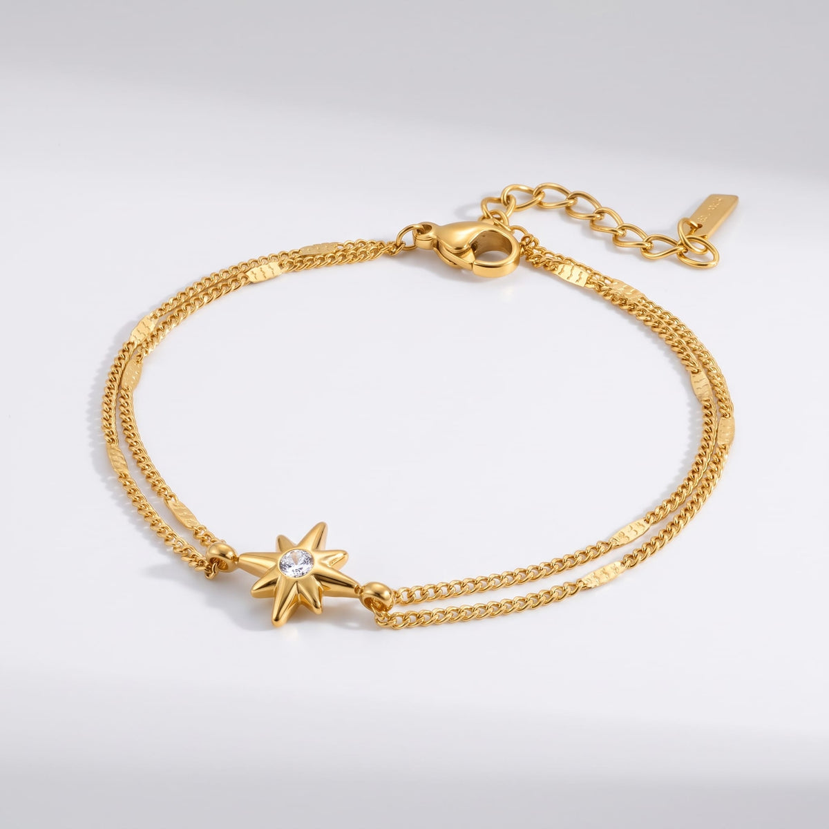 Astrid north star gold bracelet on a plain white surface showing delicate double chain detailing
