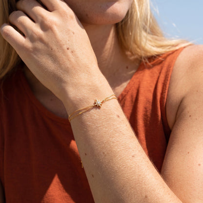 Wider view of a woman wearing the Astrid north star gold bracelet on the wrist, featuring a star charm