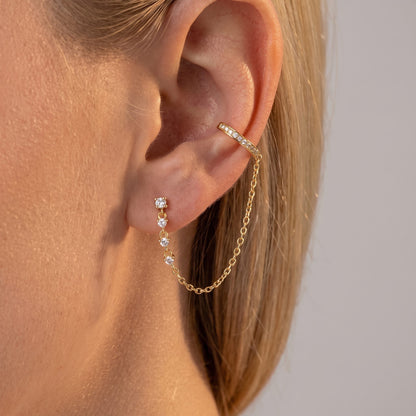 Woman wearing the Audra gold ear cuff linked by a fine chain to a crystal drop stud