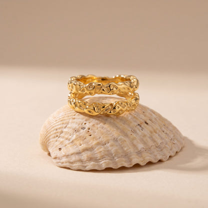 The Aurélie hammered double gold ring resting on a seashell