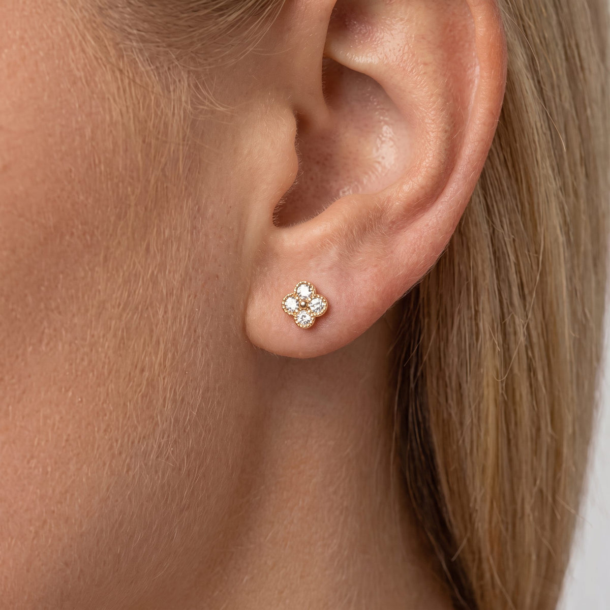 Woman wearing an Aurélie sparkle stud, a small gold clover set with clear crystals