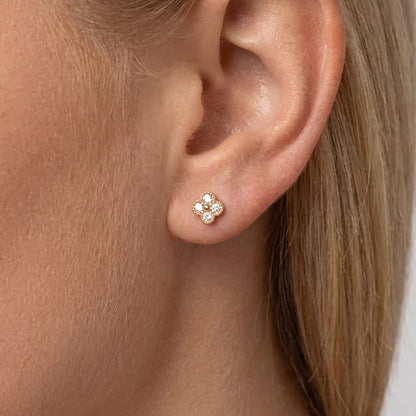 Woman wearing an Aurélie sparkle stud, a small gold clover set with clear crystals