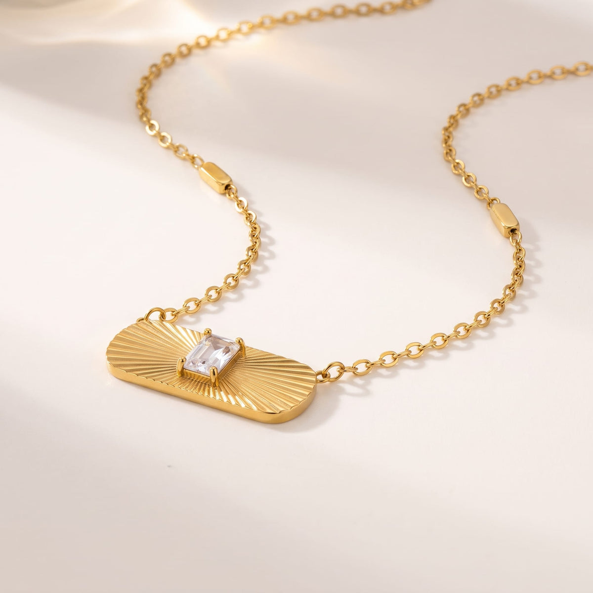 Aurora sunburst crystal gold necklace on a white background in soft natural sunlight