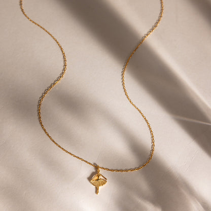 Ava ballerina necklace curving across pale linen in streaks of window shadow