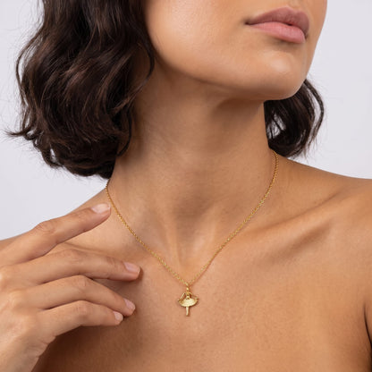Woman wearing the Ava ballerina gold necklace at the throat with her hand touching her neck