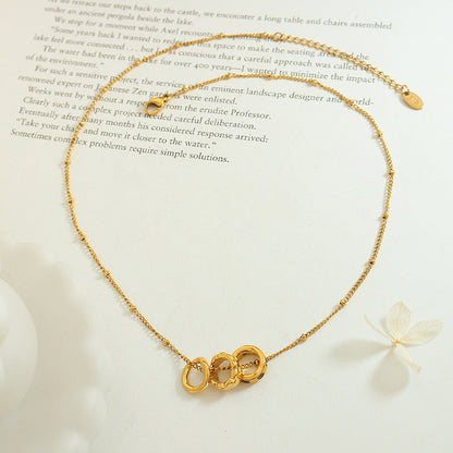 Benedetta triple ring necklace laid open on a book page with its extender chain and tag