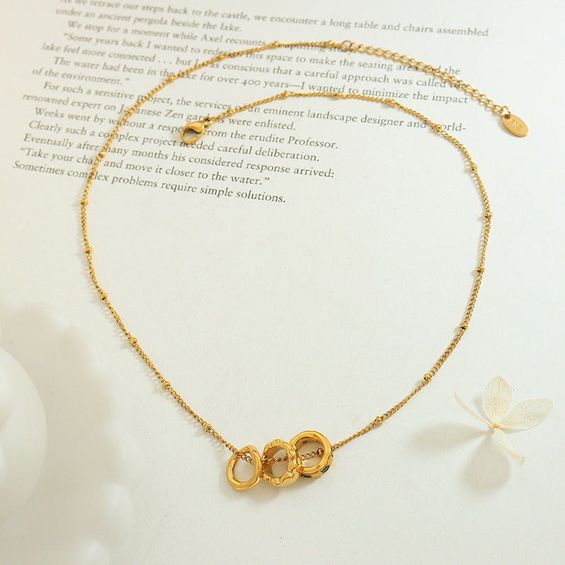 Benedetta triple ring necklace laid open on a book page with its extender chain and tag