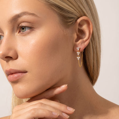 Woman wearing the Bettina crystal cascade gold earrings on her ear resting hand under chin