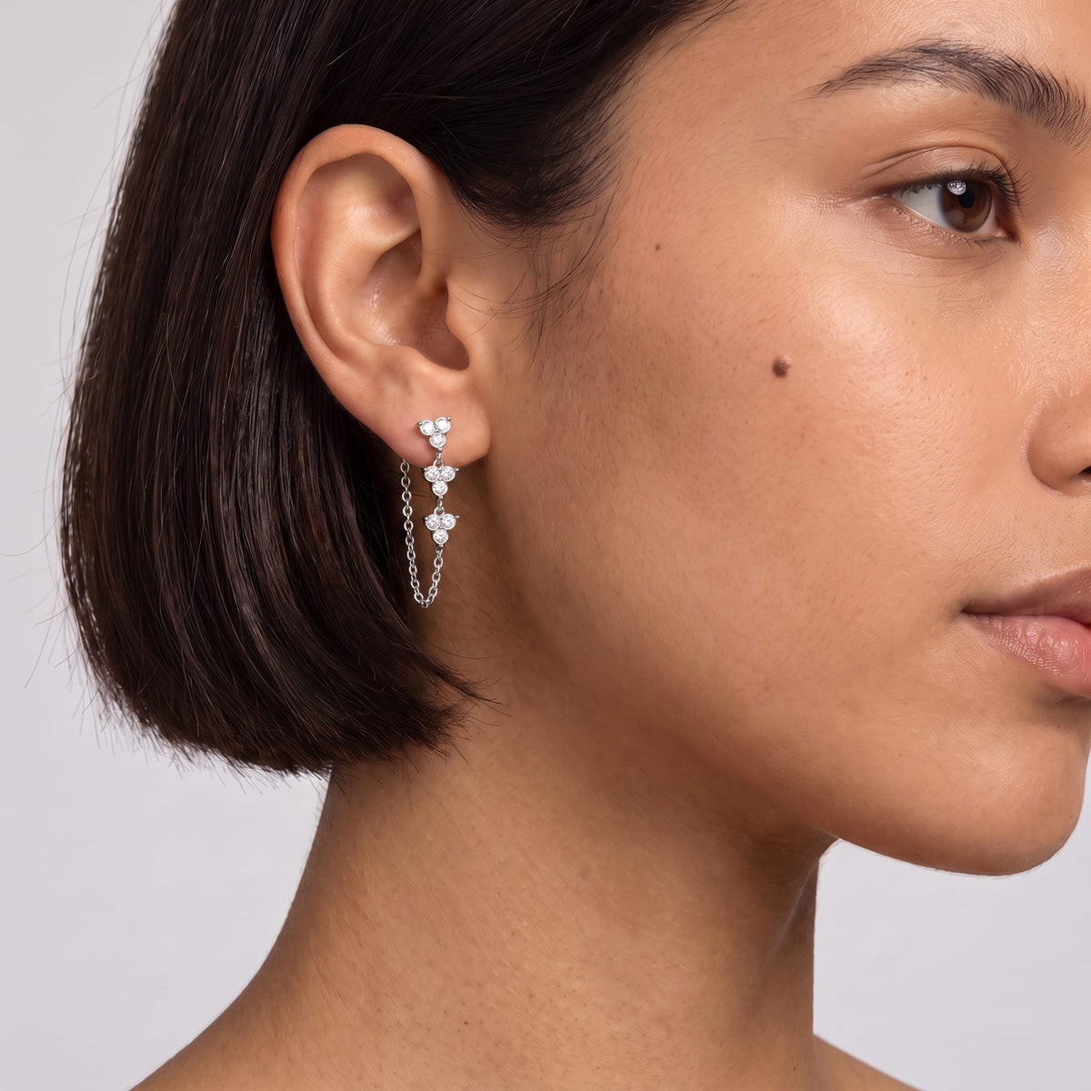 Woman wearing the Bettina crystal cascade silver earrings on her ear with short dark hair