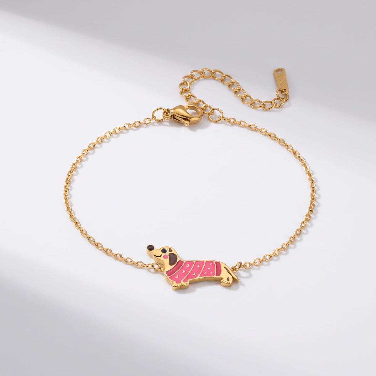 Bianca pink dachshund gold bracelet on a plain white surface with soft light