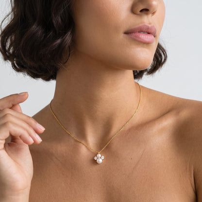 Woman wearing the Blanche pearl cluster gold necklace at the collarbone with her hand raised near her chin