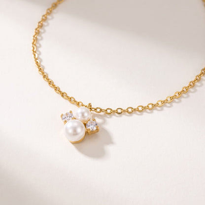 Blanche pearl cluster gold necklace on a off-white surface showing close-up details of the pendant cluster