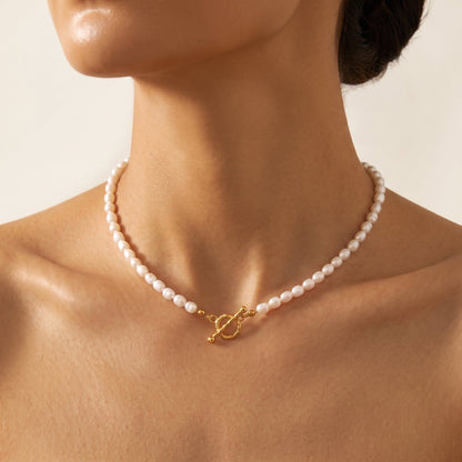 Woman wearing the Camille pearl toggle gold necklace at the collarbone