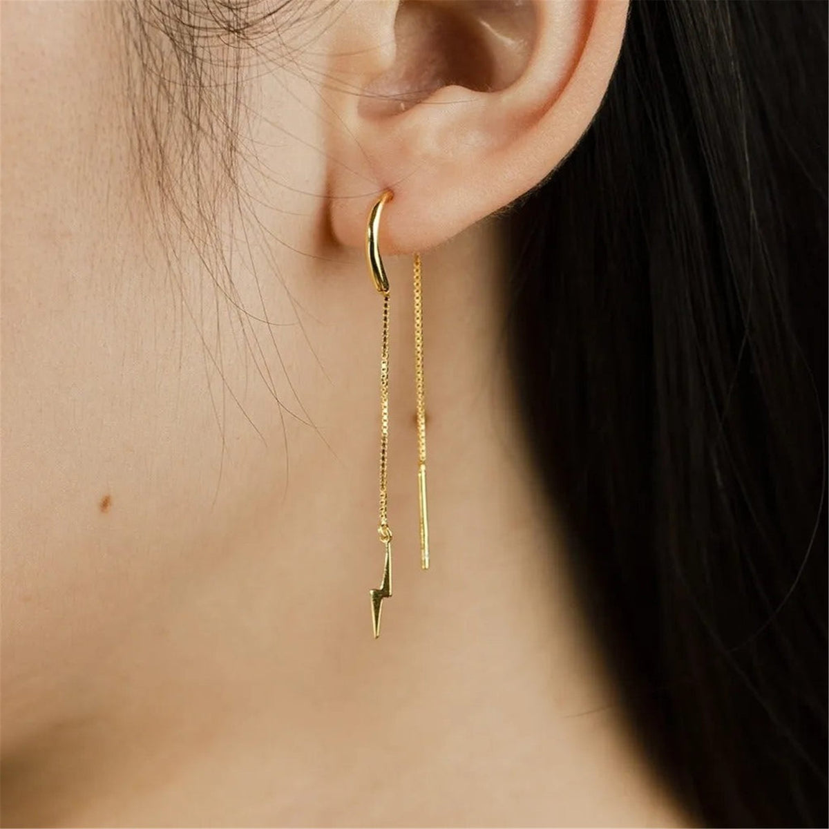 Woman wearing a Camille gold threader earring with a tiny lightning bolt charm