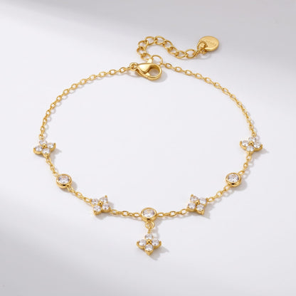 Capucine clover drop gold bracelet on a plain white surface displaying zircon clover charms and clasp
