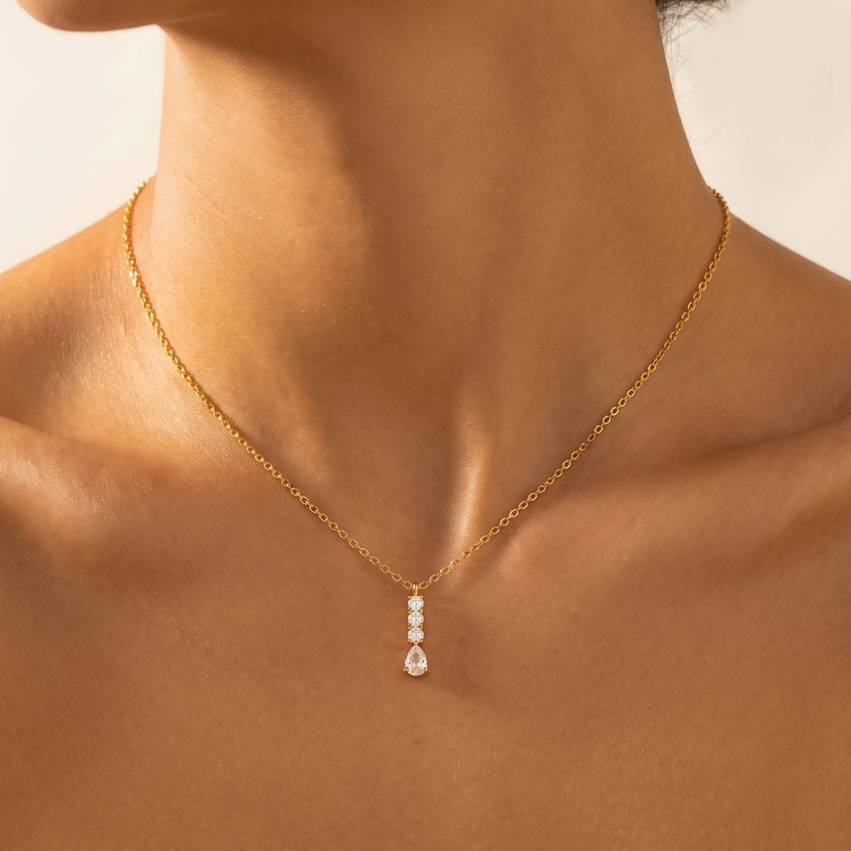 Close-up of a woman wearing the Céleste pear drop gold necklace at the base of her neck