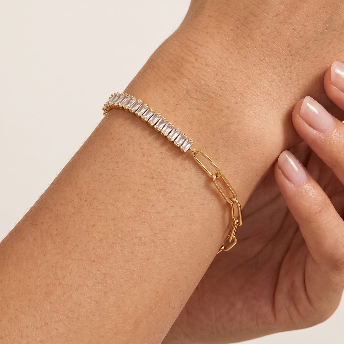 Woman wearing the Chiara baguette paperclip gold bracelet on the wrist, showcasing clear crystals