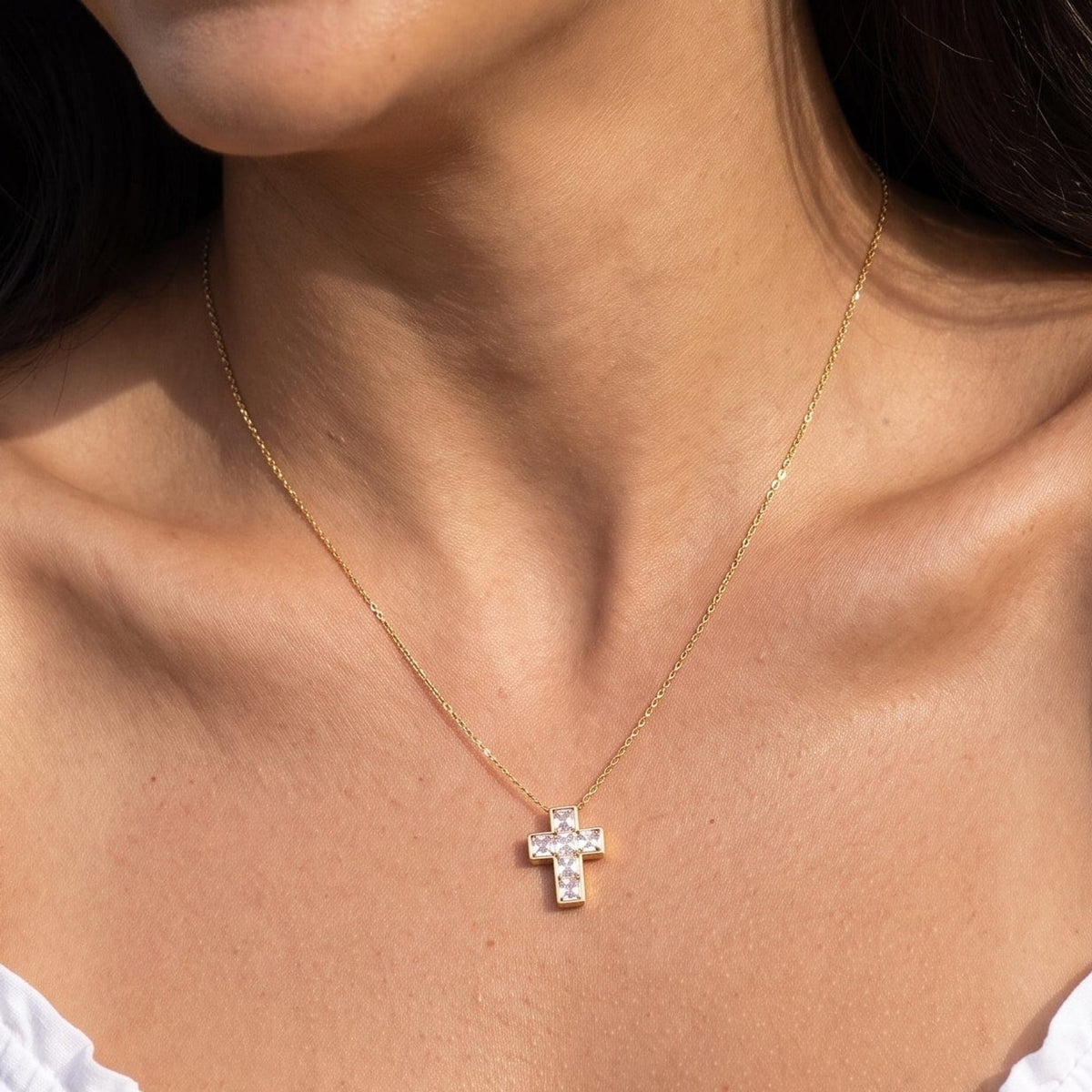 Woman wearing the Chiara crystal cross gold necklace at the collarbone
