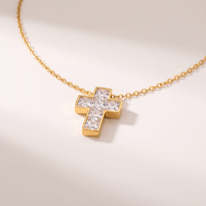 Chiara crystal cross gold necklace on a white surface with soft shadows