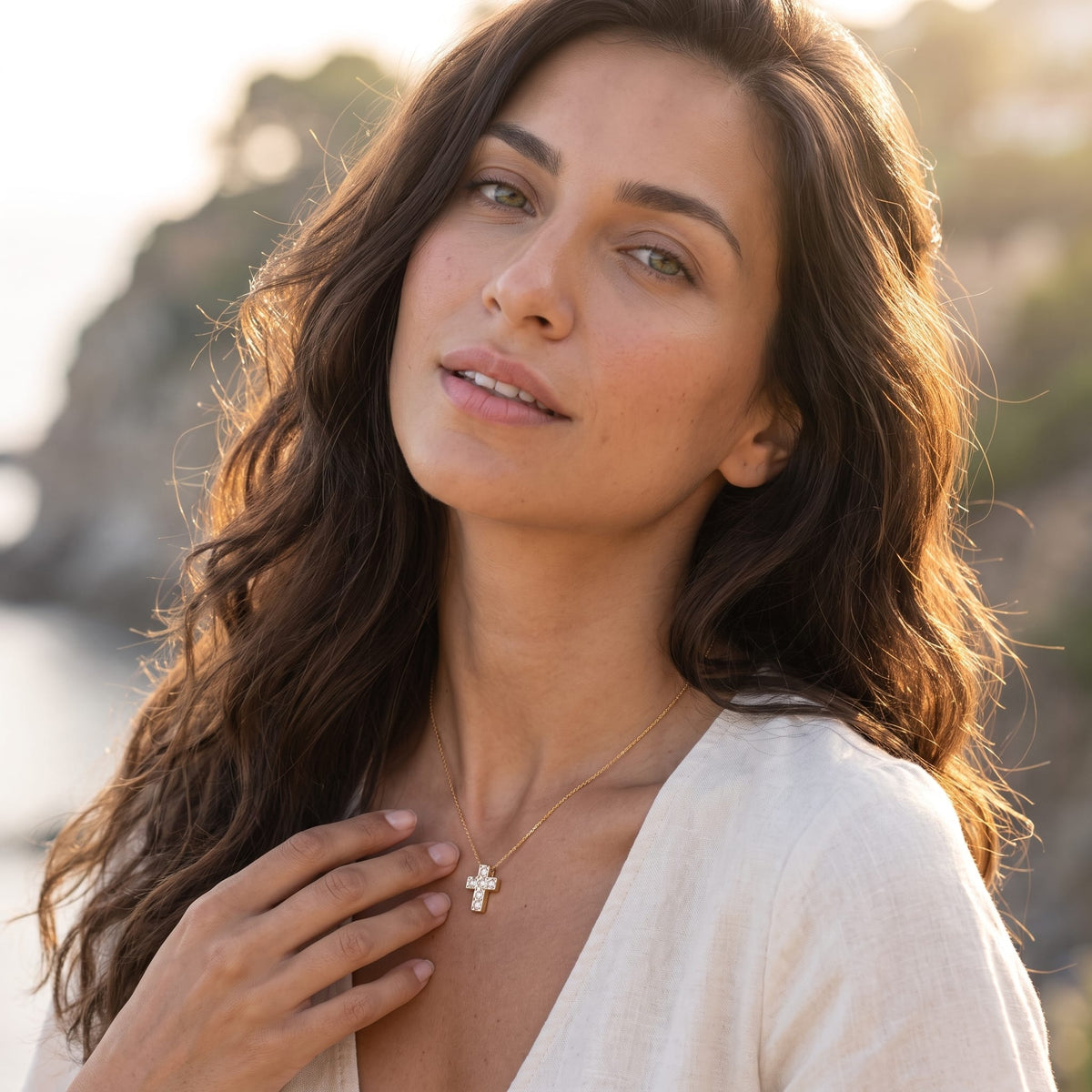 Woman wearing the Chiara crystal cross gold necklace at the collarbone in a white dress outdoors