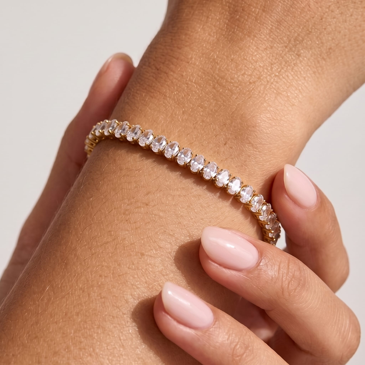 Woman wearing the Chiara oval zircon tennis bracelet on the wrist, set with clear oval crystals