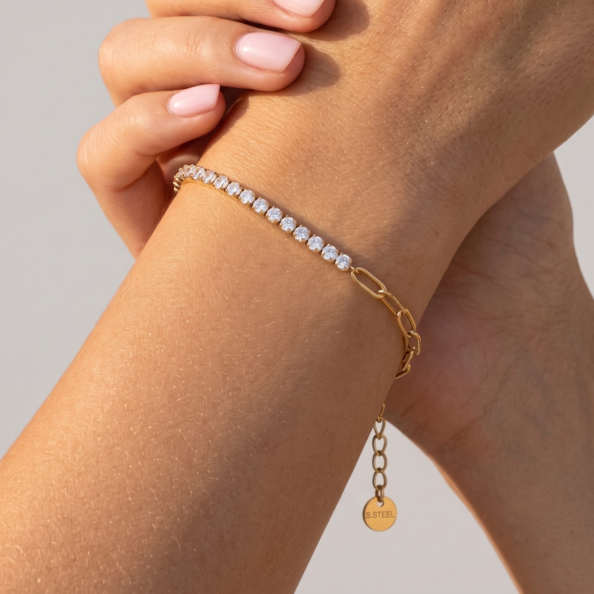 Woman wearing the Chiara gold bracelet, half crystal tennis line and half paperclip chain, on the wrist