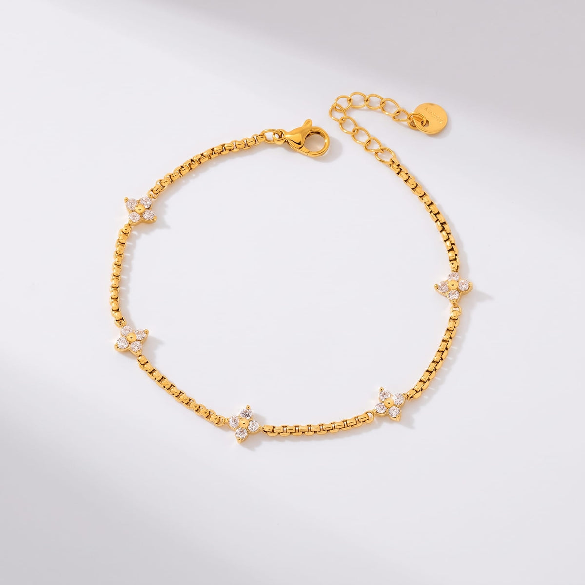 Clara crystal clover gold bracelet on a plain white surface casting soft shadows